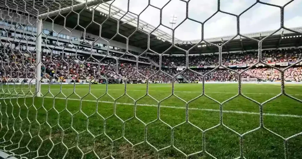 Ein Fußballtor mit engmaschigem Netz steht auf einem gepflegten Rasenplatz.