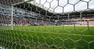 Ein Fußballtor mit engmaschigem Netz steht auf einem gepflegten Rasenplatz.